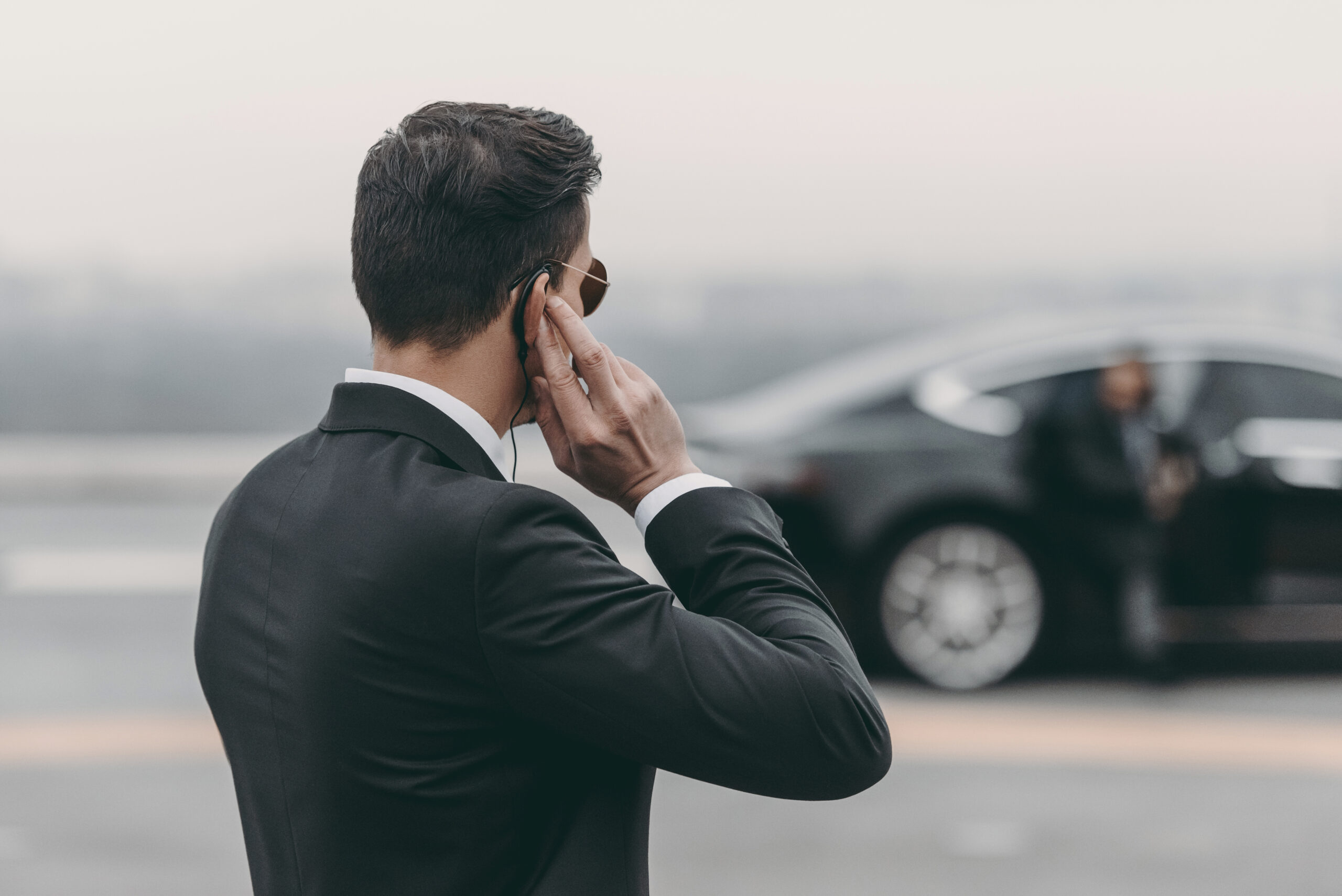 handsome bodyguard standing and listening message with security earpiece on helipad